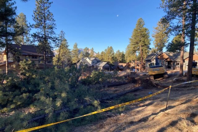 a yellow tape on a dirt road with trees and houses
